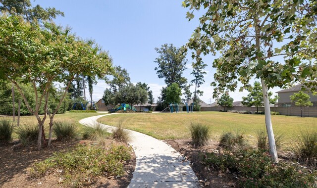 view of property's community featuring fence, a lawn, and playground community