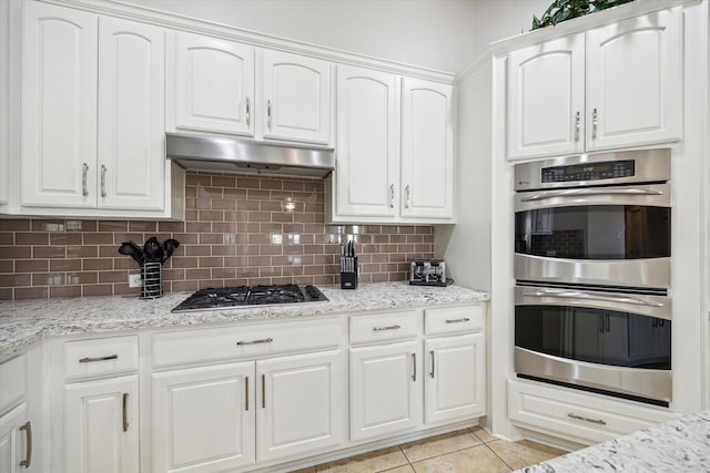 2411 Lakeway Dr, Friendswood, TX 77546 - kitchen with under cabinet range hood, backsplash, white cabinets, and appliances with stainless steel finishes