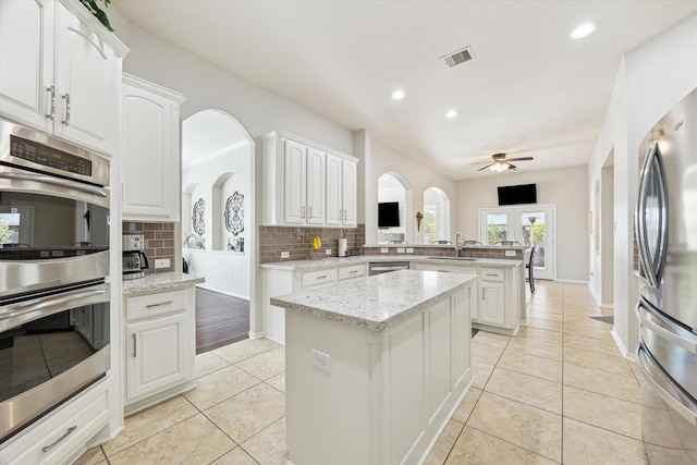 2411 Lakeway Dr, Friendswood, TX 77546 - kitchen featuring a peninsula, a sink, backsplash, light tile patterned floors, and stainless steel appliances