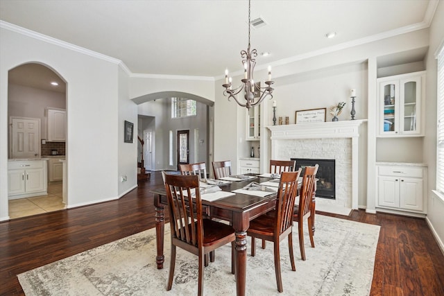2411 Lakeway Dr, Friendswood, TX 77546 - dining space with arched walkways, ornamental molding, a stone fireplace, and wood finished floors