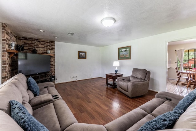 living area featuring baseboards, a textured ceiling, visible vents, and wood finished floors