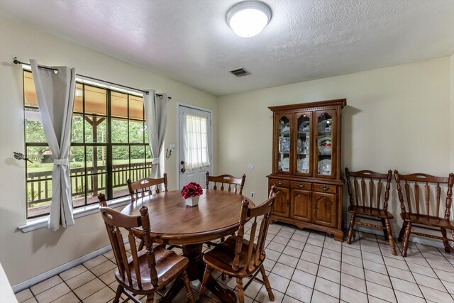 dining area featuring light tile patterned flooring, a textured ceiling, and visible vents