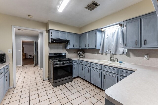 kitchen featuring visible vents, light tile patterned flooring, under cabinet range hood, stainless steel range with gas stovetop, and a sink