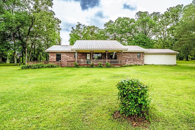rear view of property featuring brick siding, a lawn, a wooden deck, and metal roof
