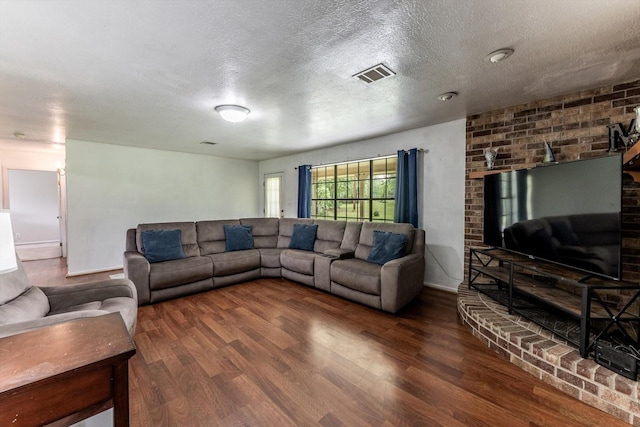 living area with baseboards, a textured ceiling, visible vents, and wood finished floors