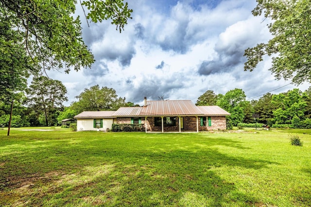 back of house with a lawn, metal roof, and brick siding