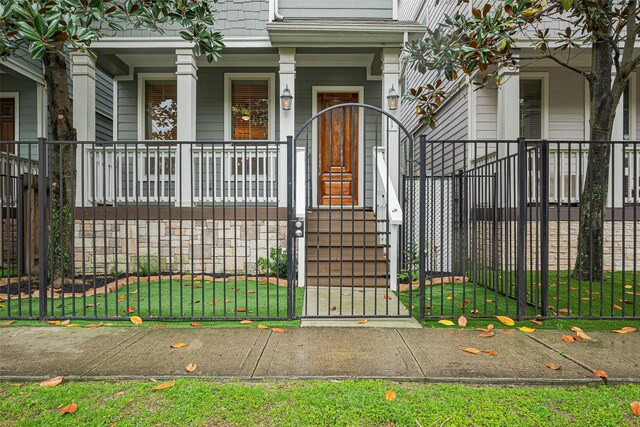 doorway to property with covered porch, fence, and a gate