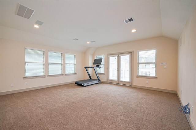 exercise room with light colored carpet, visible vents, plenty of natural light, and vaulted ceiling