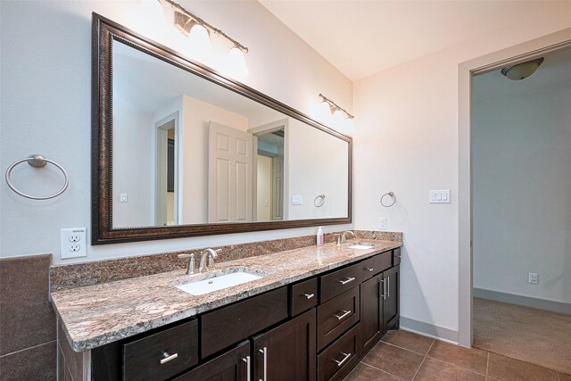 bathroom featuring double vanity, a sink, baseboards, and tile patterned floors