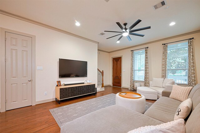living room with crown molding, wood finished floors, visible vents, and stairway