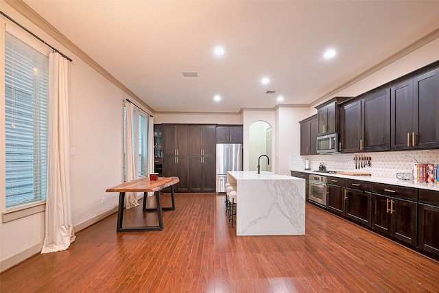 1224 Nelson Falls Ln, Houston, TX 77008 - kitchen featuring stainless steel appliances, ornamental molding, decorative backsplash, a breakfast bar area, and dark wood-style flooring