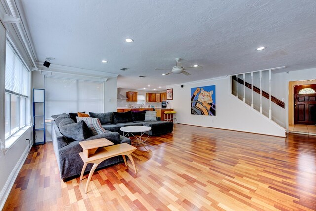 living room with ceiling fan, a textured ceiling, light wood-type flooring, stairway, and recessed lighting