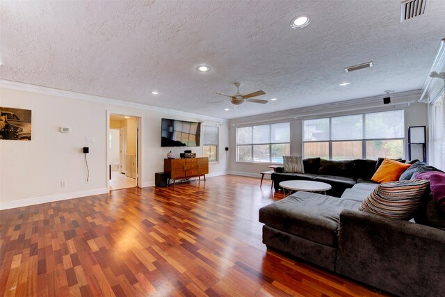 living room with crown molding, a ceiling fan, wood finished floors, and visible vents