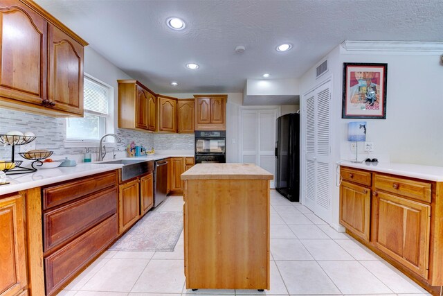 kitchen featuring backsplash, visible vents, a center island, light countertops, and black appliances