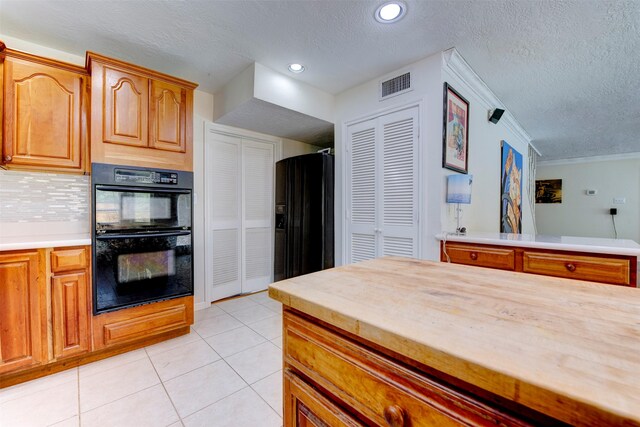 kitchen featuring dobule oven black, decorative backsplash, visible vents, a textured ceiling, and light tile patterned floors