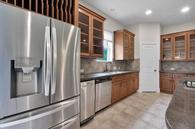 73 La Jolla Cir, Montgomery, TX 77356 - kitchen featuring dark countertops, appliances with stainless steel finishes, a sink, brown cabinetry, and backsplash