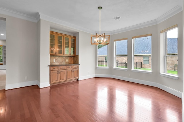 73 La Jolla Cir, Montgomery, TX 77356 - unfurnished dining area with crown molding, an inviting chandelier, baseboards, wood finished floors, and visible vents