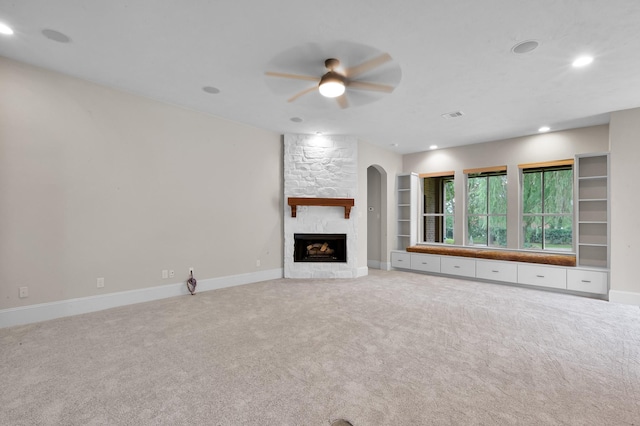 73 La Jolla Cir, Montgomery, TX 77356 - unfurnished living room featuring ceiling fan, light carpet, arched walkways, a stone fireplace, and recessed lighting