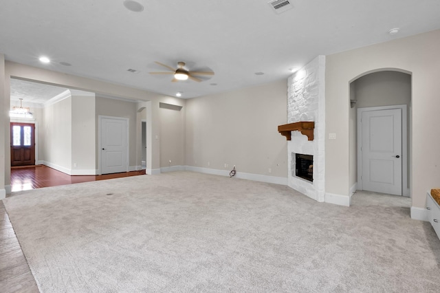 73 La Jolla Cir, Montgomery, TX 77356 - unfurnished living room featuring visible vents, carpet floors, a stone fireplace, arched walkways, and a ceiling fan