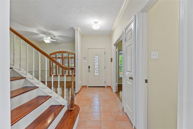 4614 Ringrose Dr, Missouri City, TX 77459 - foyer entrance featuring crown molding, light tile patterned flooring, ceiling fan, a textured ceiling, and stairway