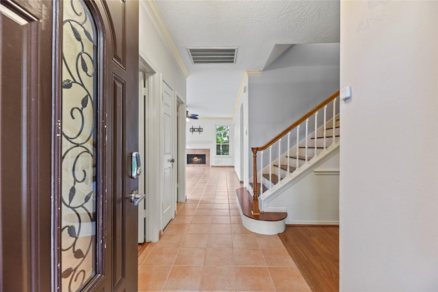 4614 Ringrose Dr, Missouri City, TX 77459 - foyer entrance with a warm lit fireplace, baseboards, light tile patterned floors, visible vents, and stairway