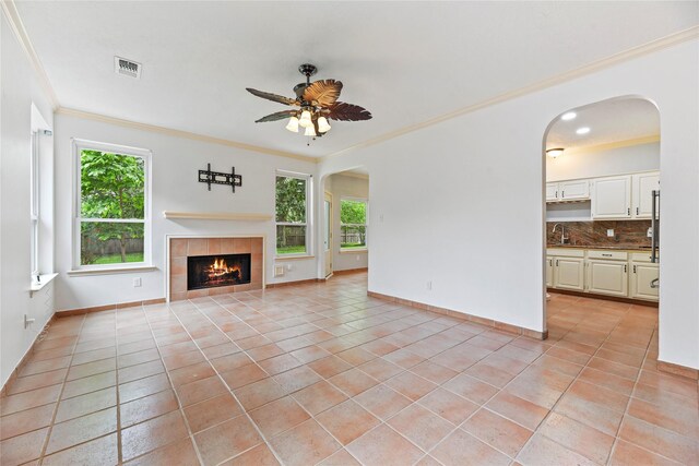 4614 Ringrose Dr, Missouri City, TX 77459 - unfurnished living room featuring light tile patterned floors, arched walkways, ornamental molding, and a ceiling fan