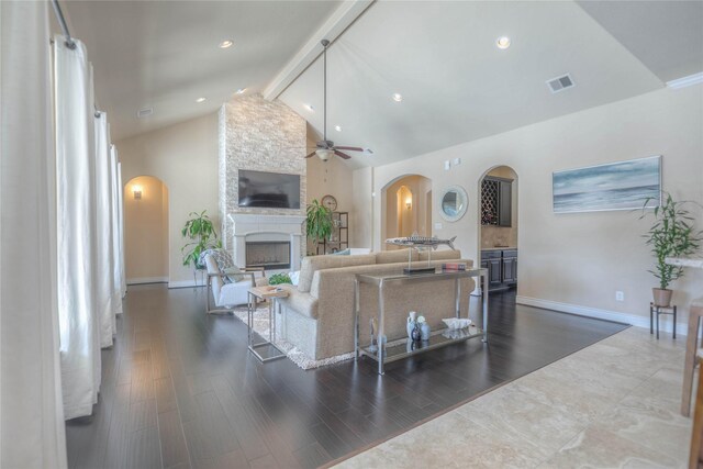 living room with arched walkways, a ceiling fan, visible vents, and a fireplace