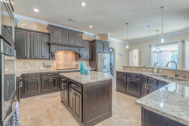 kitchen featuring visible vents, ornamental molding, a center island, a sink, and appliances with stainless steel finishes