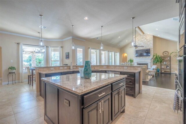 kitchen with a large fireplace, a kitchen island with sink, open floor plan, and lofted ceiling