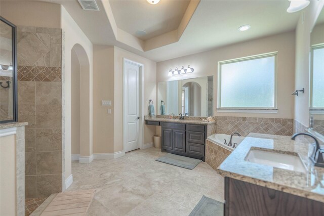 full bathroom with a sink, walk in shower, a garden tub, and visible vents