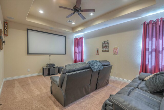 home theater with light colored carpet, a raised ceiling, a ceiling fan, recessed lighting, and visible vents