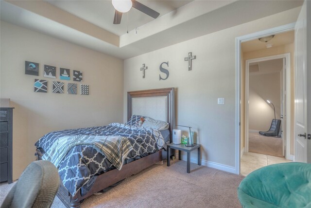 bedroom featuring carpet floors, baseboards, ceiling fan, and a raised ceiling