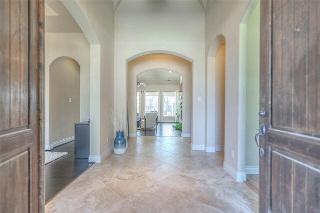 foyer featuring arched walkways, baseboards, and a ceiling fan