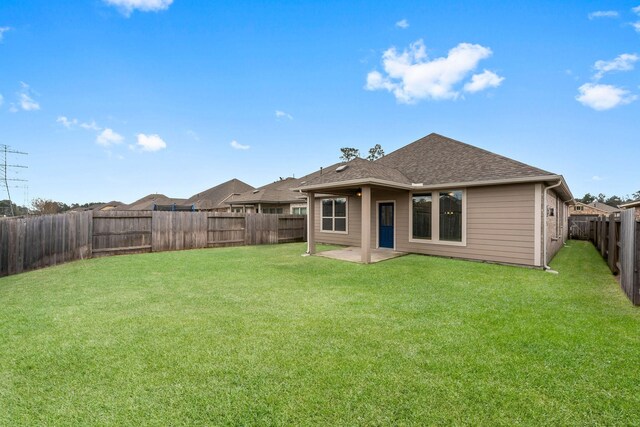 back of house with a yard, a shingled roof, a fenced backyard, and a patio area
