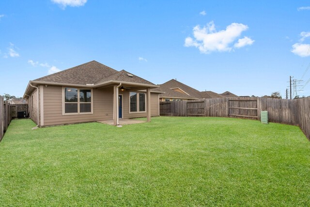 rear view of property with a fenced backyard, a shingled roof, and a yard