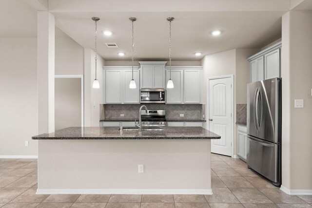 kitchen featuring visible vents, dark stone counters, a sink, appliances with stainless steel finishes, and backsplash