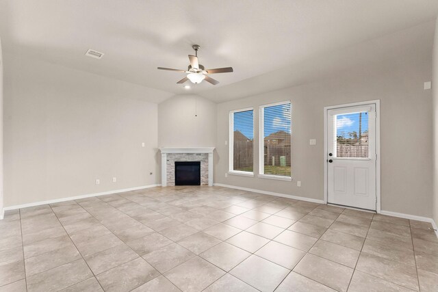 unfurnished living room featuring a stone fireplace, a ceiling fan, baseboards, and light tile patterned floors