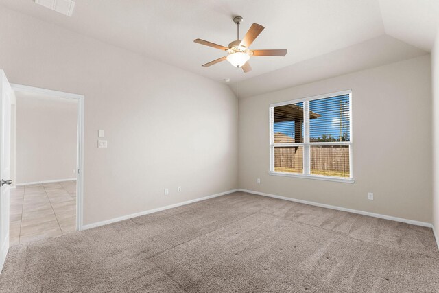 spare room featuring a ceiling fan, light colored carpet, visible vents, vaulted ceiling, and baseboards