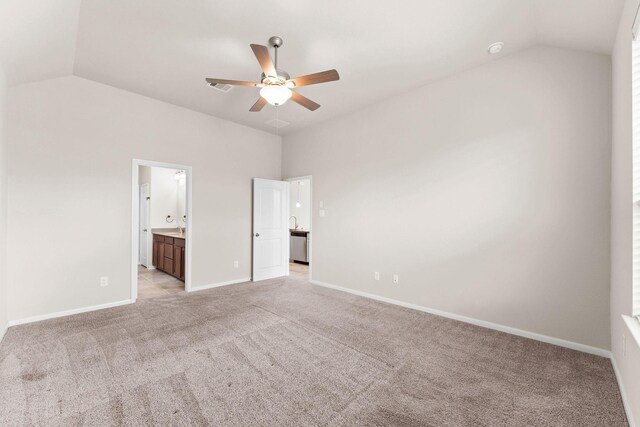 unfurnished bedroom with baseboards, vaulted ceiling, ensuite bath, and light colored carpet