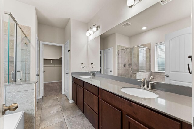 bathroom featuring visible vents, tile patterned floors, a spacious closet, a shower stall, and a sink