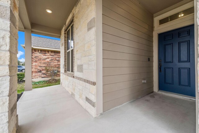 view of exterior entry featuring brick siding and stone siding