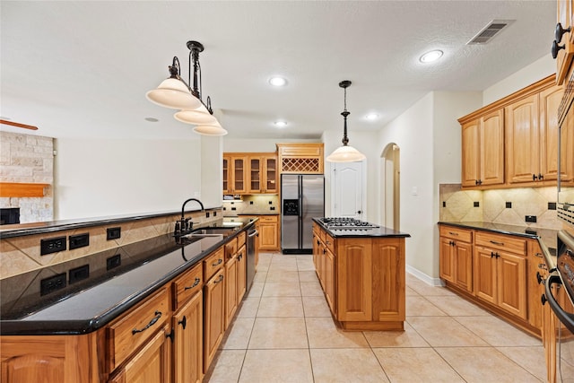 kitchen featuring a kitchen island, visible vents, tasteful backsplash, a sink, and stainless steel appliances