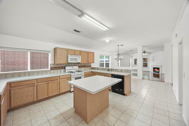 kitchen featuring a sink, white appliances, a peninsula, a lit fireplace, and visible vents