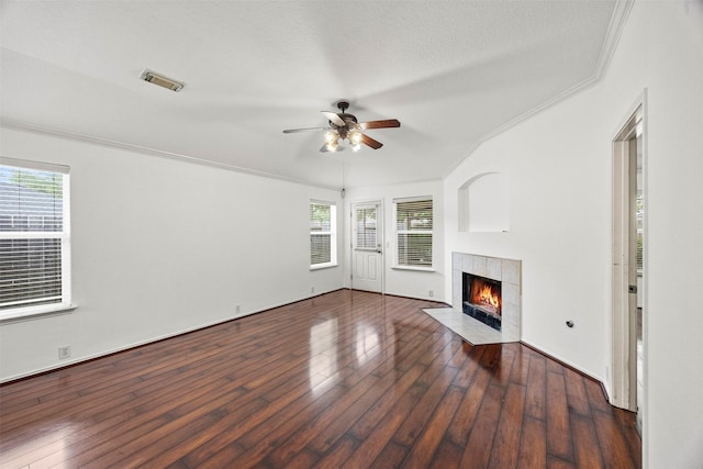 unfurnished living room with crown molding, a fireplace, a ceiling fan, a wealth of natural light, and visible vents