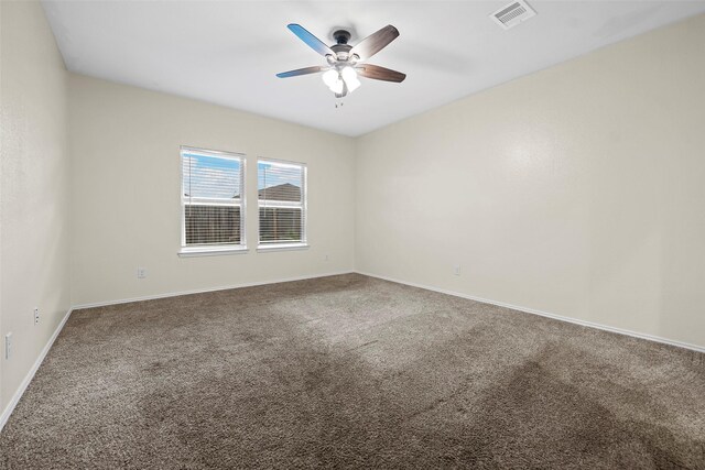 carpeted spare room with visible vents, a ceiling fan, and baseboards