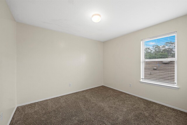 carpeted empty room featuring baseboards