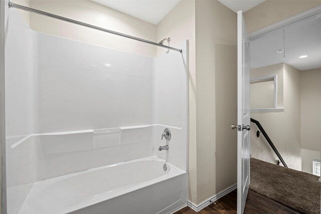 full bath with baseboards, washtub / shower combination, and wood finished floors