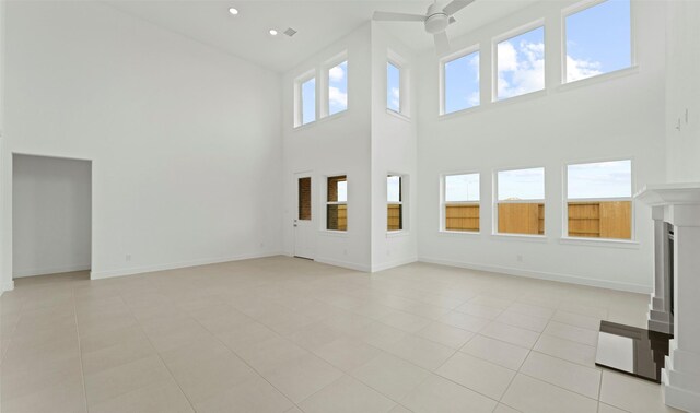 unfurnished living room featuring light tile patterned floors, baseboards, a ceiling fan, and a towering ceiling