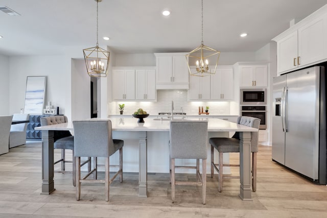 kitchen featuring light countertops, appliances with stainless steel finishes, tasteful backsplash, and a notable chandelier
