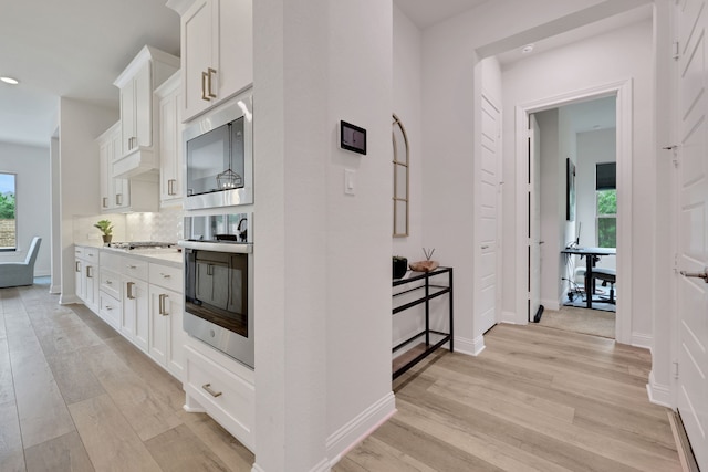 kitchen featuring a healthy amount of sunlight, appliances with stainless steel finishes, white cabinets, and light wood-type flooring